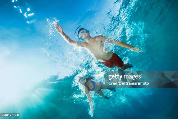 young man and woman snorkeling  underwater diving adventure  turquoise sea - underwater diving stock pictures, royalty-free photos & images