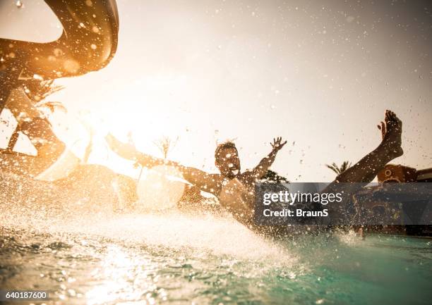 man having fun while sliding into the swimming pool. - water park stock pictures, royalty-free photos & images