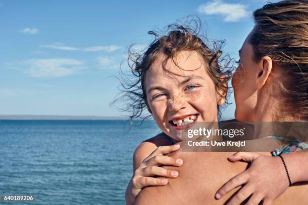 portrait of girl hugging her mum on beach, smiling - portrait beach stockfoto's en -beelden