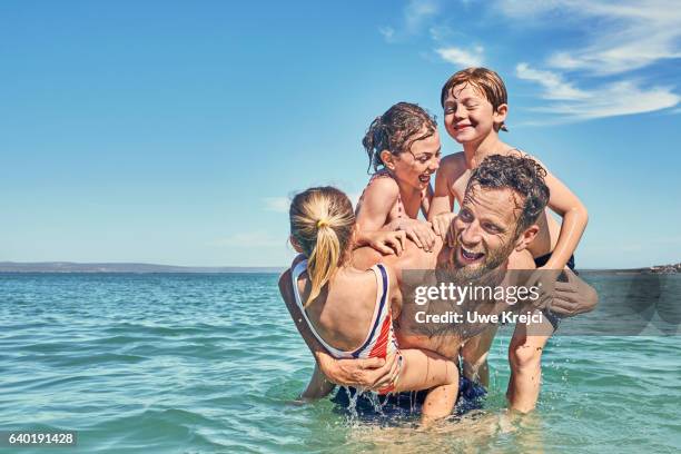 father playing with his three children in the sea - père célibataire photos et images de collection