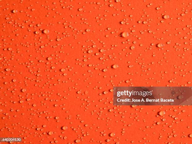 full frame thick textures on a paper of carton wetted with water drops of orange color - orange colour background stock pictures, royalty-free photos & images