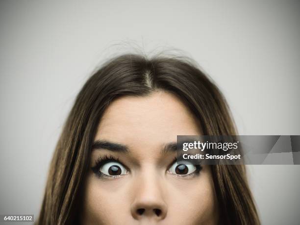 surprised woman smiling against gray background - eye open stockfoto's en -beelden