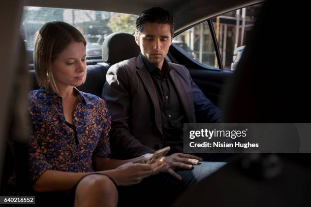 man and woman sitting in car looking at phone - management car smartphone stock pictures, royalty-free photos & images