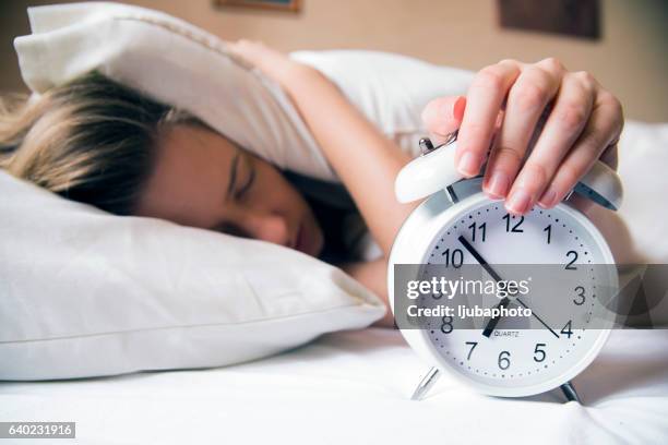 young beautiful blonde woman lying in bed suffering from alarm - alarmklok stockfoto's en -beelden