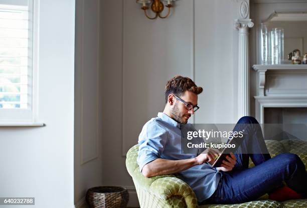 chilling at home with his tablet - sofa tablet stock pictures, royalty-free photos & images