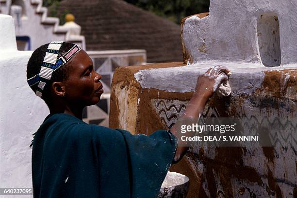 Ndebele woman decorating a village wall, Botshabelo township, Transvaal, South Africa.
