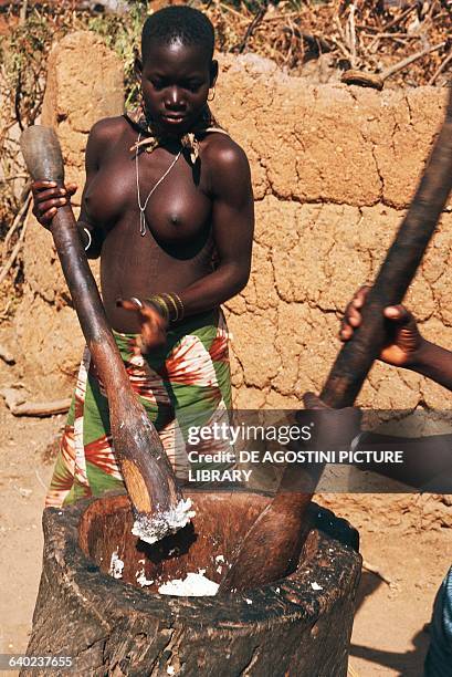 Young Bariba woman pounding yams, Benin.