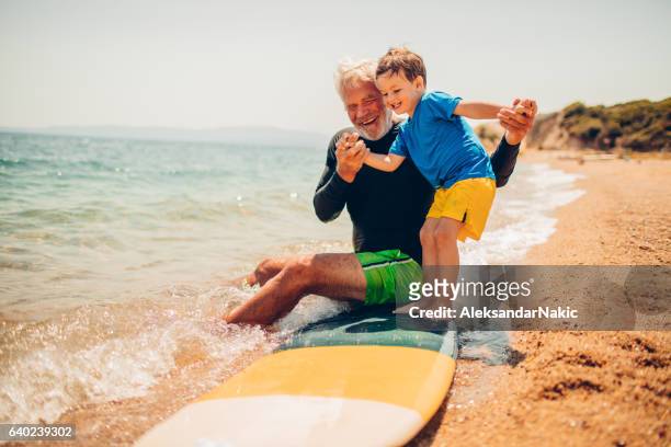 basics of surfing with my grandpa - multi generation family beach stock pictures, royalty-free photos & images