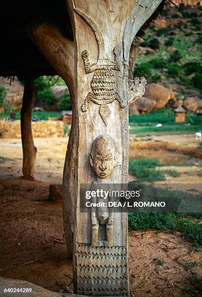Carved wooden pole from a toguna, meeting house for the elders at the centre of a Dogon village, Kundu, with the Bandiagara Escarpment in the...