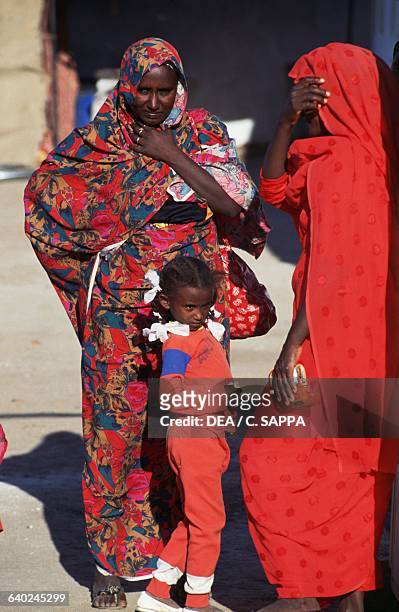 Two female wedding guests and a little girl in colourful clothes, Kerma, Nubia, Karmah, Sudan.
