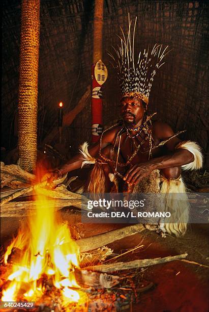 Sangoma, , in front of a fire, Zulu village, KwaZulu-Natal, South Africa.