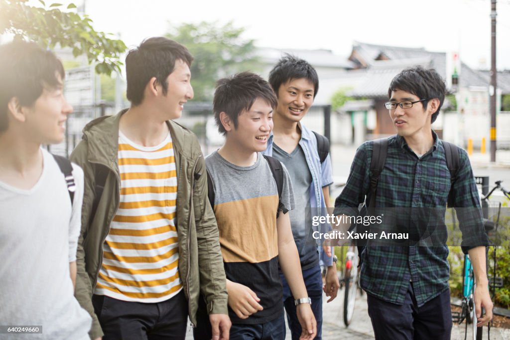 Young man talking with college friends on sidewalk