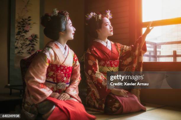 young geisha girls looking through window - geisha in training stock pictures, royalty-free photos & images