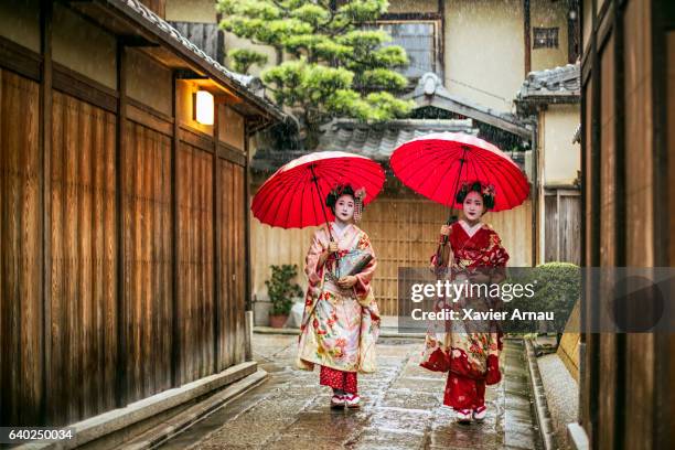 geishas holding red umbrellas during rainy season - maiko imagens e fotografias de stock