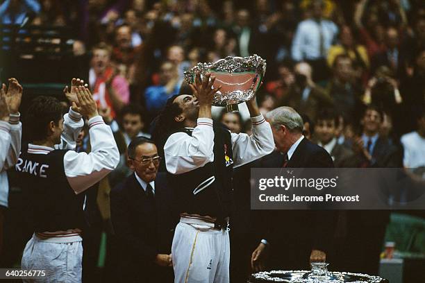 France's captain Yannick Noah holds the trophy after the French team defeats the USA in the 1991 Davis Cup tennis final .