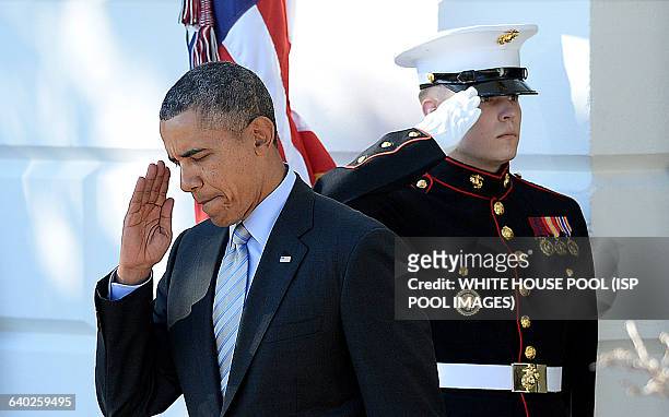 President Barack Obama salutes a Marines as he arrives at a ceremony to honor the 2012-2013 NCAA Division I Men's and Women's Champions on the South...