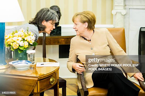 German Chancellor Angela Merkel talks with an aide before a bilateral meeting with U.S. President Barack Obama in the Oval Office at the White House...