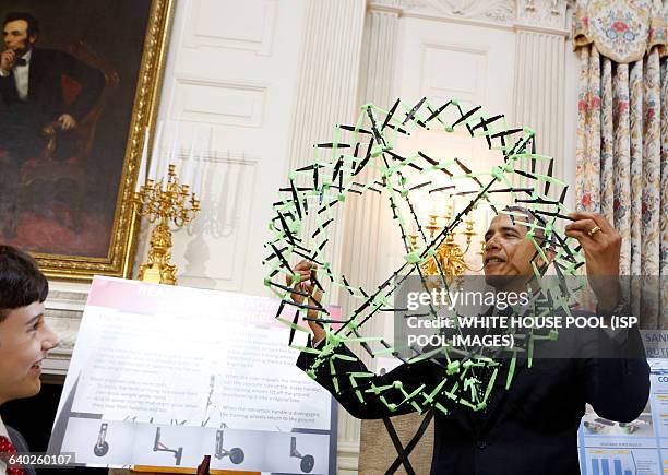 President Barack Obama looks at the project of Peyton Roberston from Ft Lauderdale, FL, winner of the Discovery 3M Young Scientist, for his "Sandless...