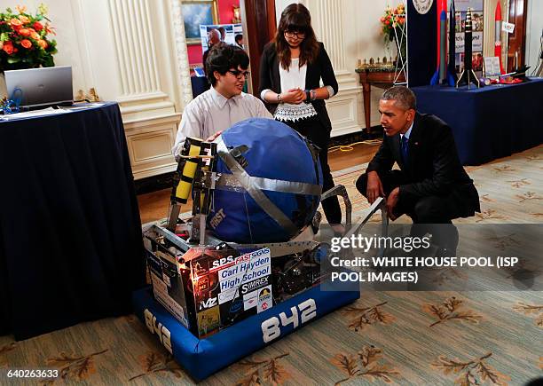 Us President Barack Obama looks at the invention of Sergio Corral and Isela Martinez from Phoenix, AZ, leaders of the robotics program from Carl...