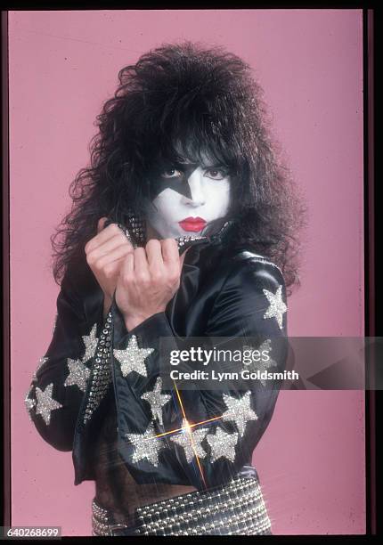 Portrait of KISS guitarist and vocalist Paul Stanley, in full make-up. He is shown holding up the collar of his jacket, which has sequined stars...