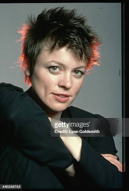 Closeup of performance artist and musician Laurie Anderson. Her arms are crossed across her knee. Undated photograph.