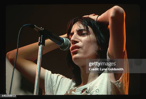 Punk rock singer and poet Patti Smith sings with her hands on her head.