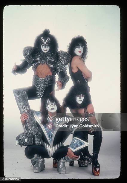 Studio portrait of the whole rock & roll band Kiss, shown full-length against a white background.