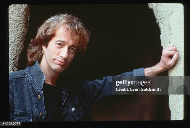 Photo shows Robin Gibb, sibling member of the singing group The Bee Gees, posed in a stone entranceway.