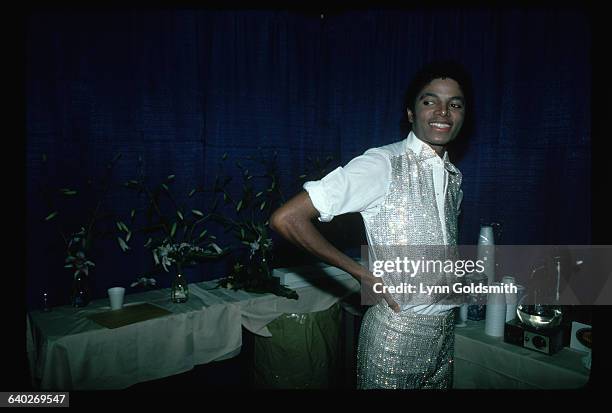 Informal portrait of Michael Jackson. He is shown waist-up, standing beside a coffee machine. Photograph, 1981.