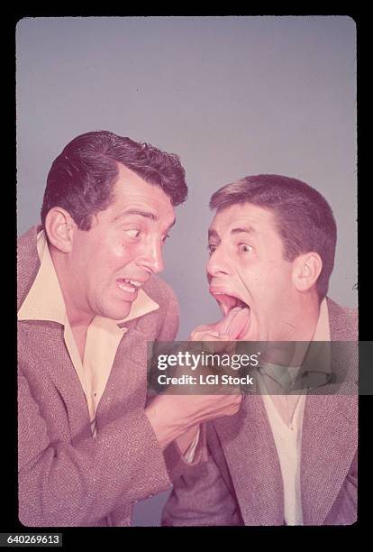 Actor Dean Martin and actor/comedian Jerry Lewis are shown in a gag pose. Martin is shown pulling on Lewis' tongue. Undated, ca. 1940s-1950s.