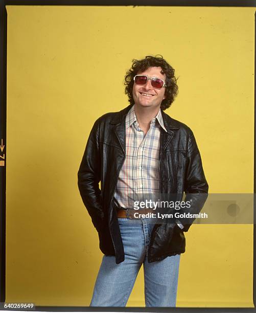 Pop singer/songwriter Randy Newman is shown in a 3/4 length studio portrait, smiling and wearing sunglasses. Undated.