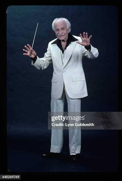 Conductor Arthur Fiedler is shown with a baton in his hand, as if conducting, in a studio potrait.