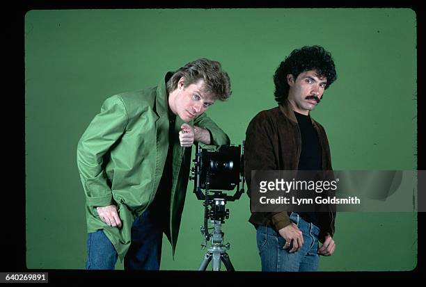 Picture shows pop artists, Daryl Hall and John Oates, poising in front of a green background next to a studio camera.