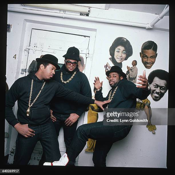 Run-DMC, a hip hop rap group, pose in front of a wall with images of jazz musicians. Rappers Run, Joe Simmons, and DMC, Darryl McDaniels, make up the...