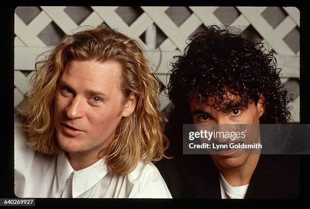 Darryl Hall and John Oates are shown in a studio portrait, in front of a trellis.