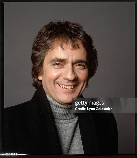 Studio headshot of actor Dudley Moore. He is shown smiling, wearing a turtleneck sweater. Undated photograph.