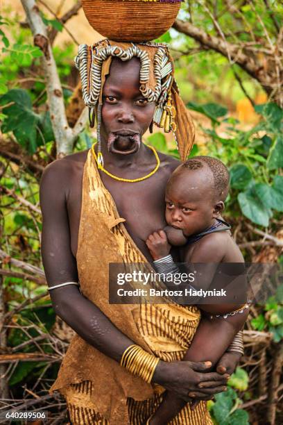 femme de culture mursi breasfeeding son bébé, éthiopie, afrique - culture tribale africaine photos et images de collection