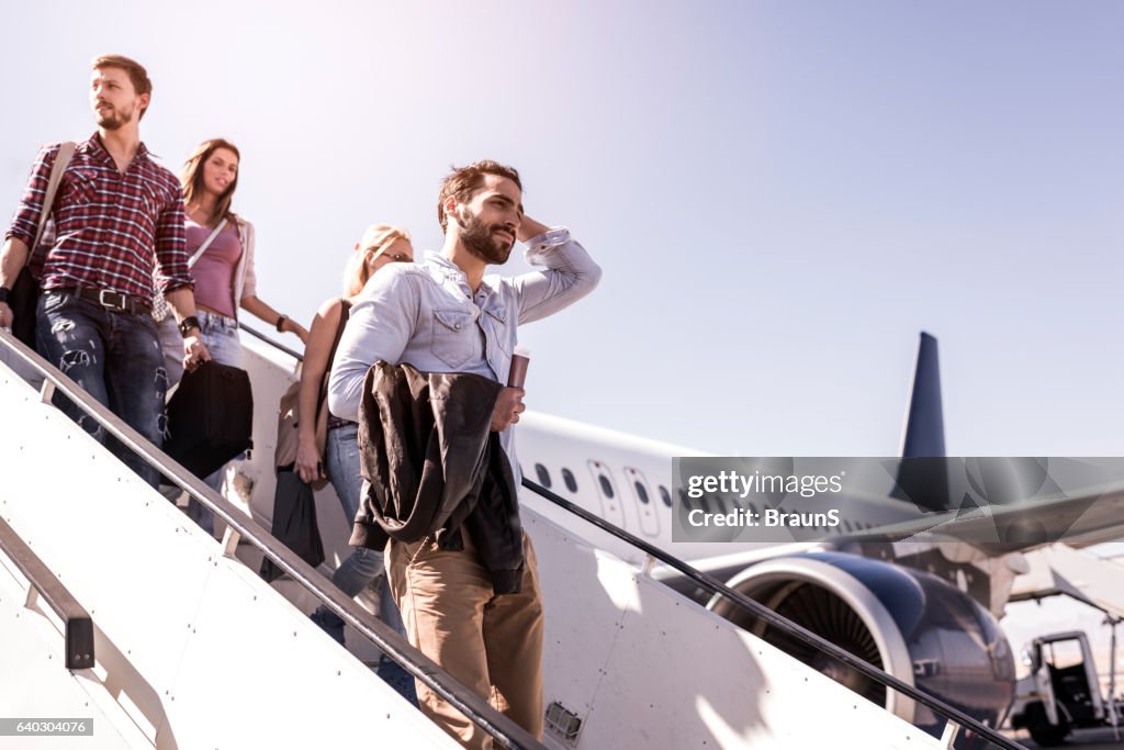 Group of young passengers disembarking the airplane.