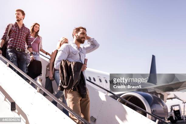group of young passengers disembarking the airplane. - leaving imagens e fotografias de stock