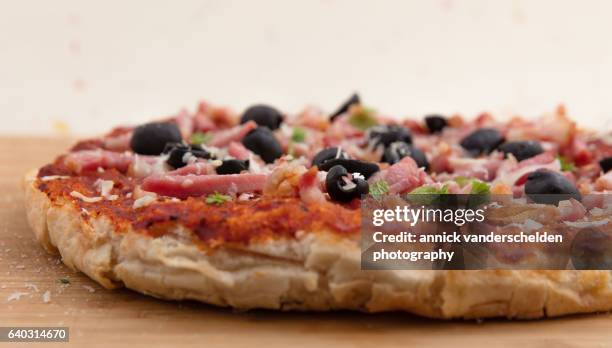 pizza with passata, olives, lardons and parmigiano-reggiano after being in the oven. - pizza crispy stock-fotos und bilder