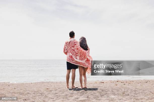 couple standing on the beach looking at the ocean - west asia stock-fotos und bilder