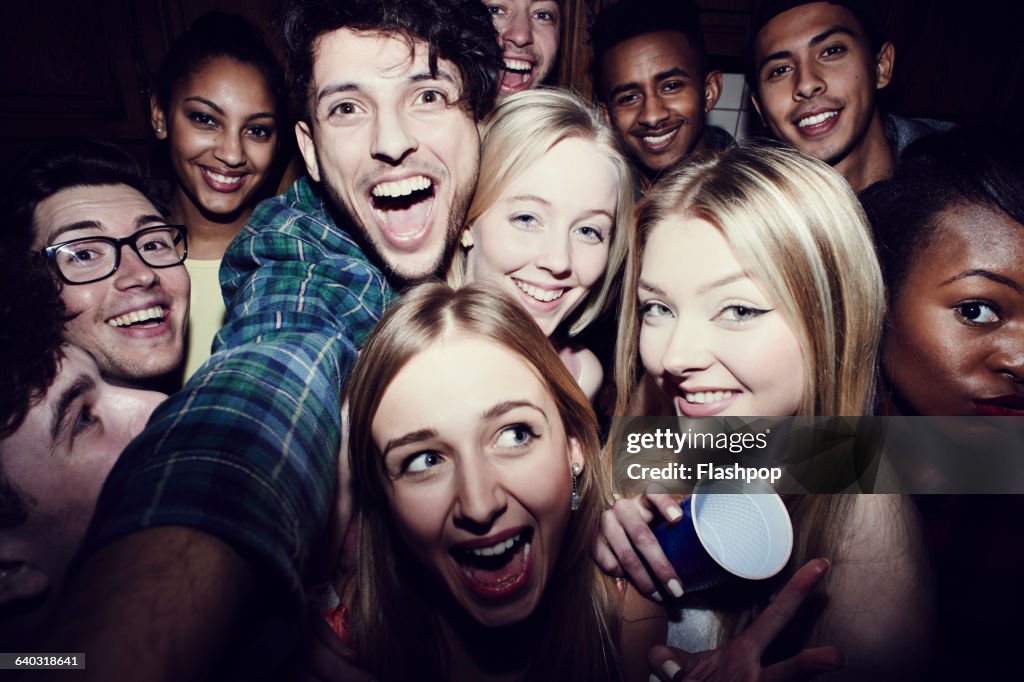 Group of friends taking selfies at a party