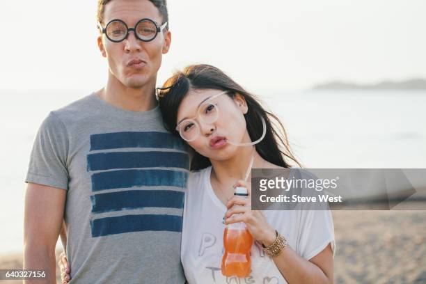 young couple wearing fun glasses on the beach - west asia stock-fotos und bilder
