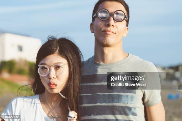 young couple wearing fun glasses on the beach - west asian ethnicity stockfoto's en -beelden