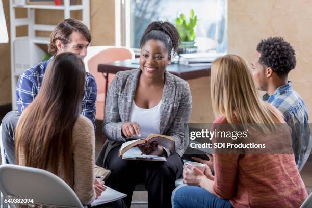 beautiful african american leads diverse bible study group - bible stockfoto's en -beelden