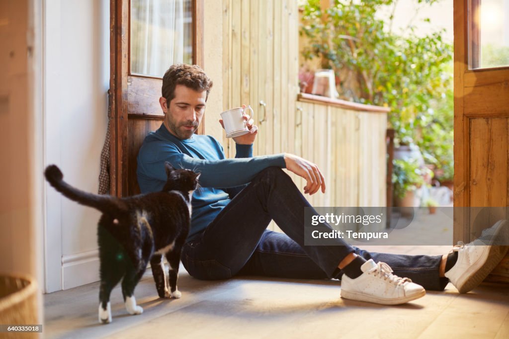 Enjoying a cup of tea sitting on the ground.