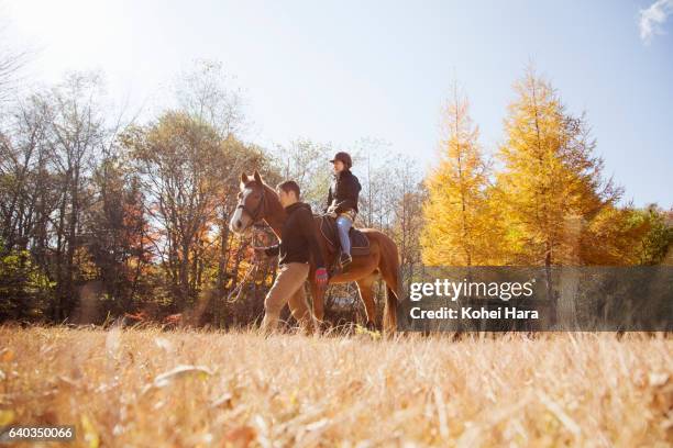 man leading woman who is riding on horse in the mountain - riding hat fotografías e imágenes de stock