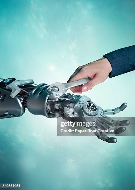 human hand fixing a robot hand with a wrench - crazy inventor stock pictures, royalty-free photos & images