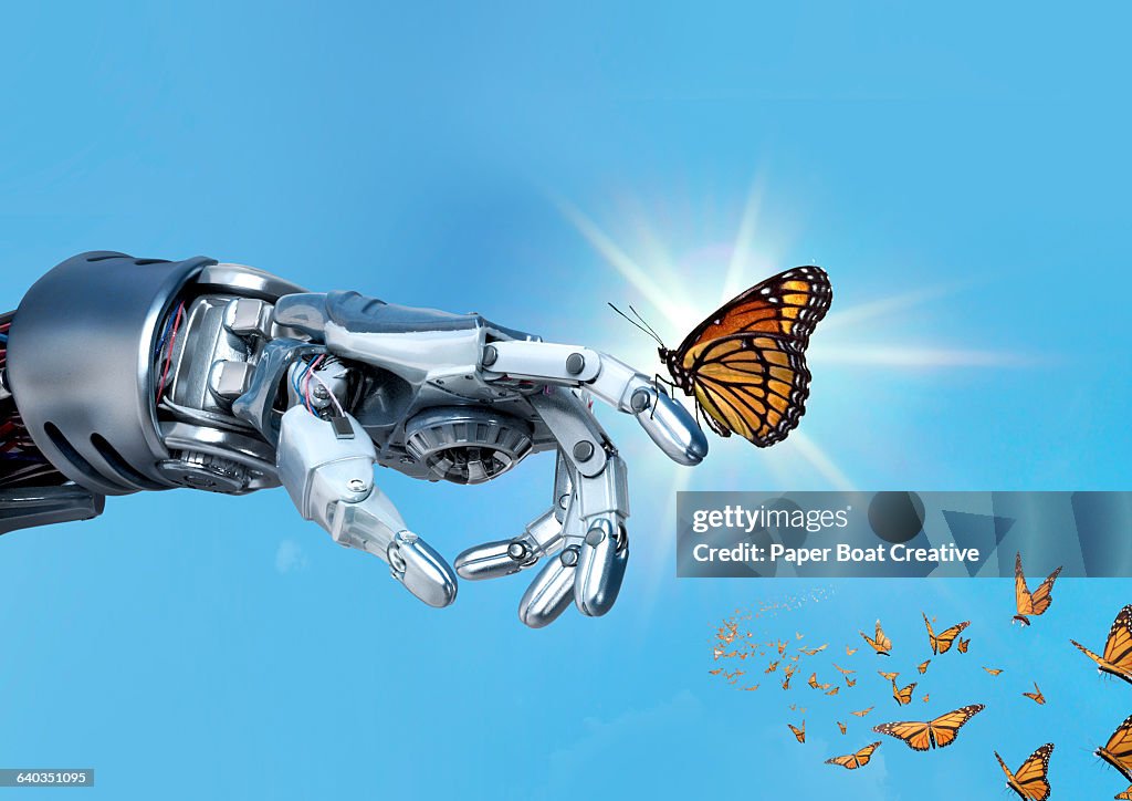 Robot hand holding an orange monarch butterfly
