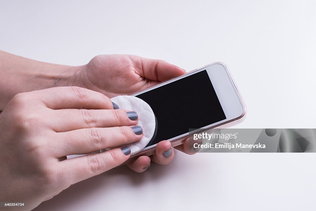 Woman hand cleaning mobile phone display